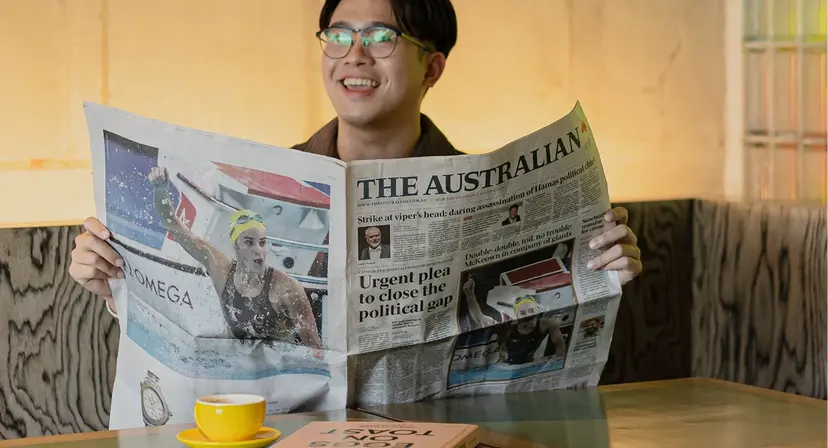 Person reading newspaper with coffee cup